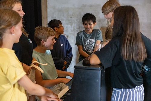 Billede af børn og unge rundt om et klaver til Bandfabrik